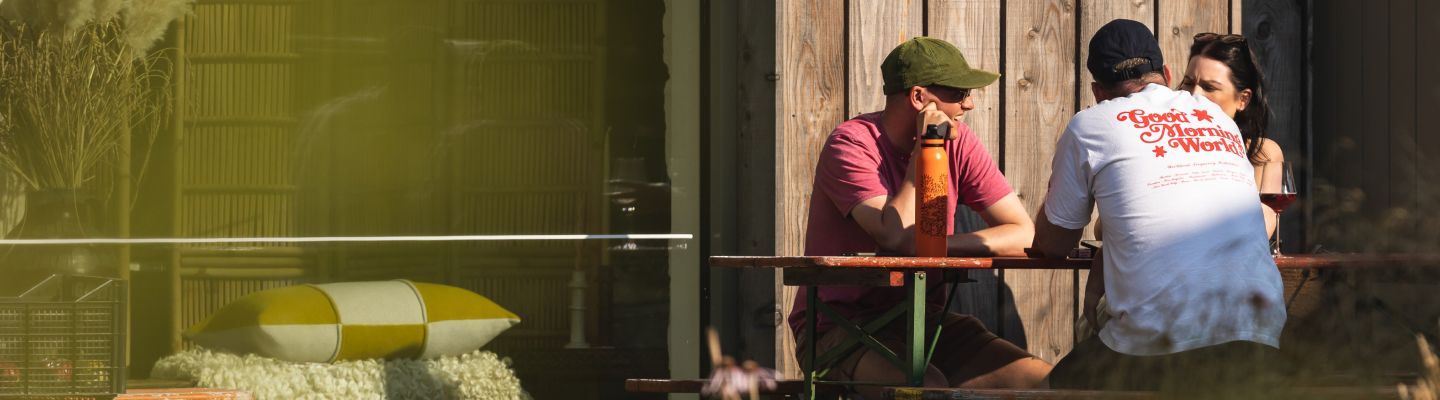 People sitting outside infront of a wooden cladded building at Tillingham